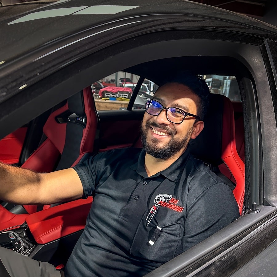 High-performance car driver smiling inside a sports car at 5ive Performance, showcasing automotive e.