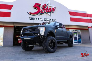 Off-road truck with large tires parked at 5 Star Tires and Wheels service center.