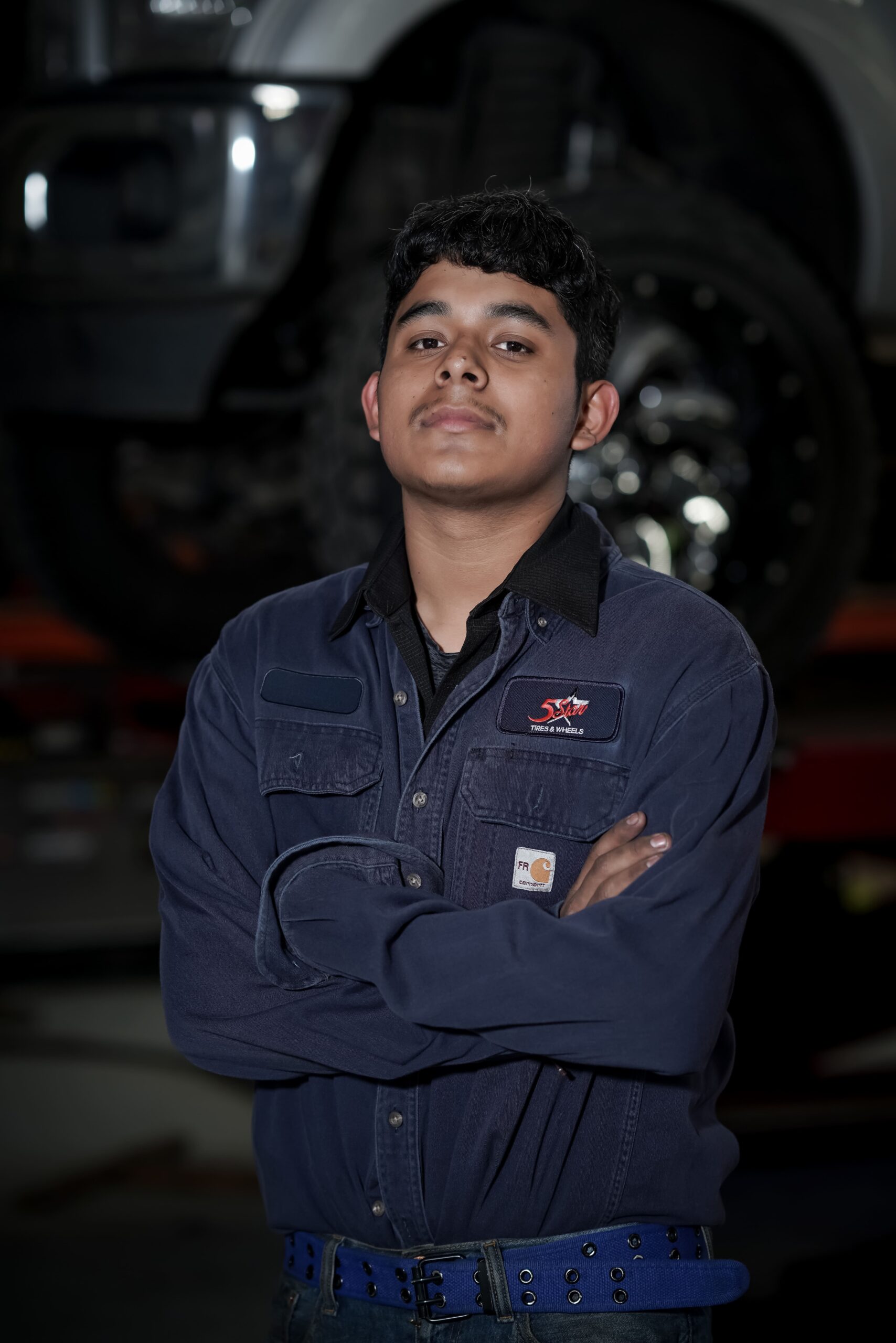 Vehicle technician at 5 Star Tires and Wheels standing confidently in the workshop.