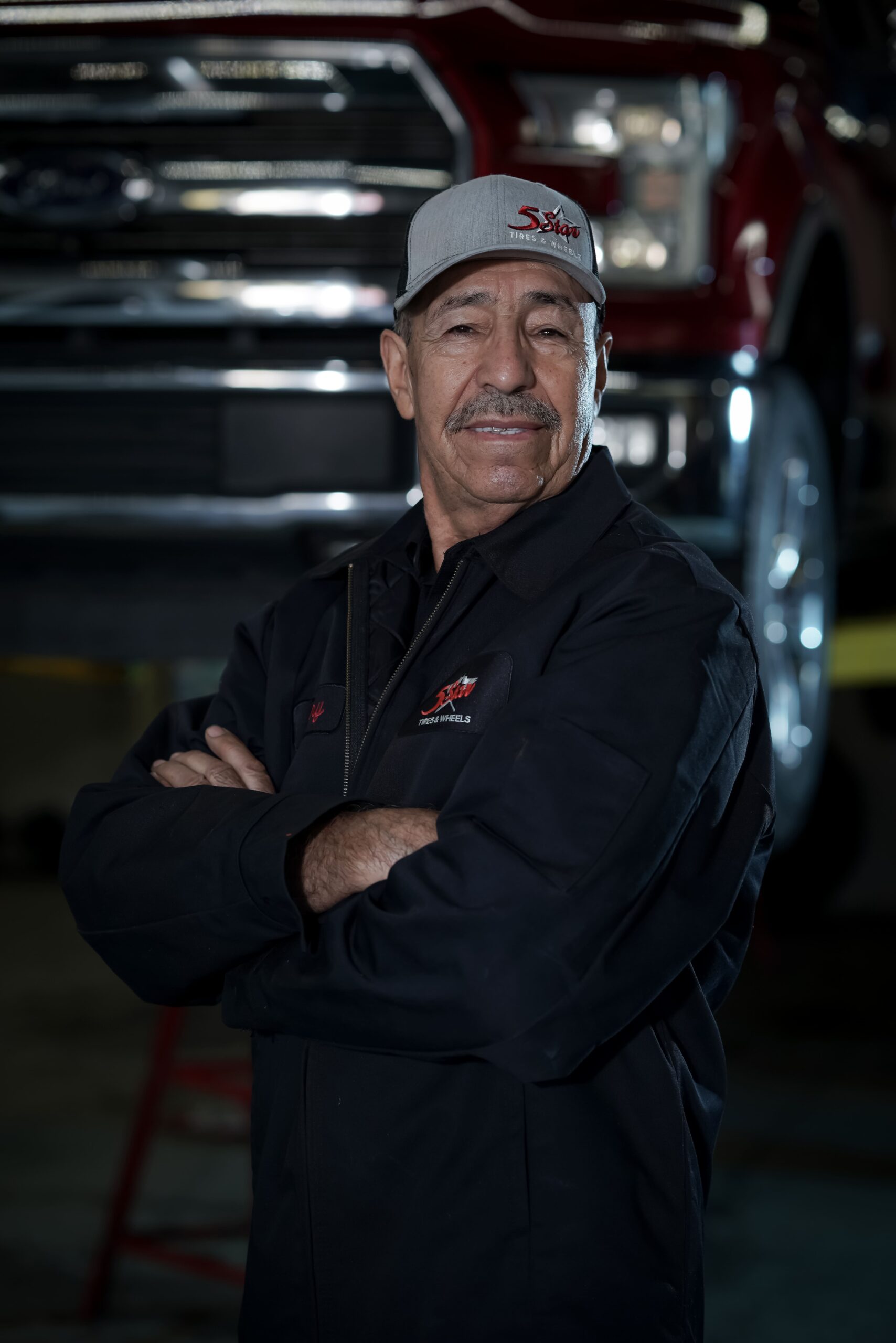 Truck technician with crossed arms in garage, showcasing expertise in tire and wheel services at 5 S.