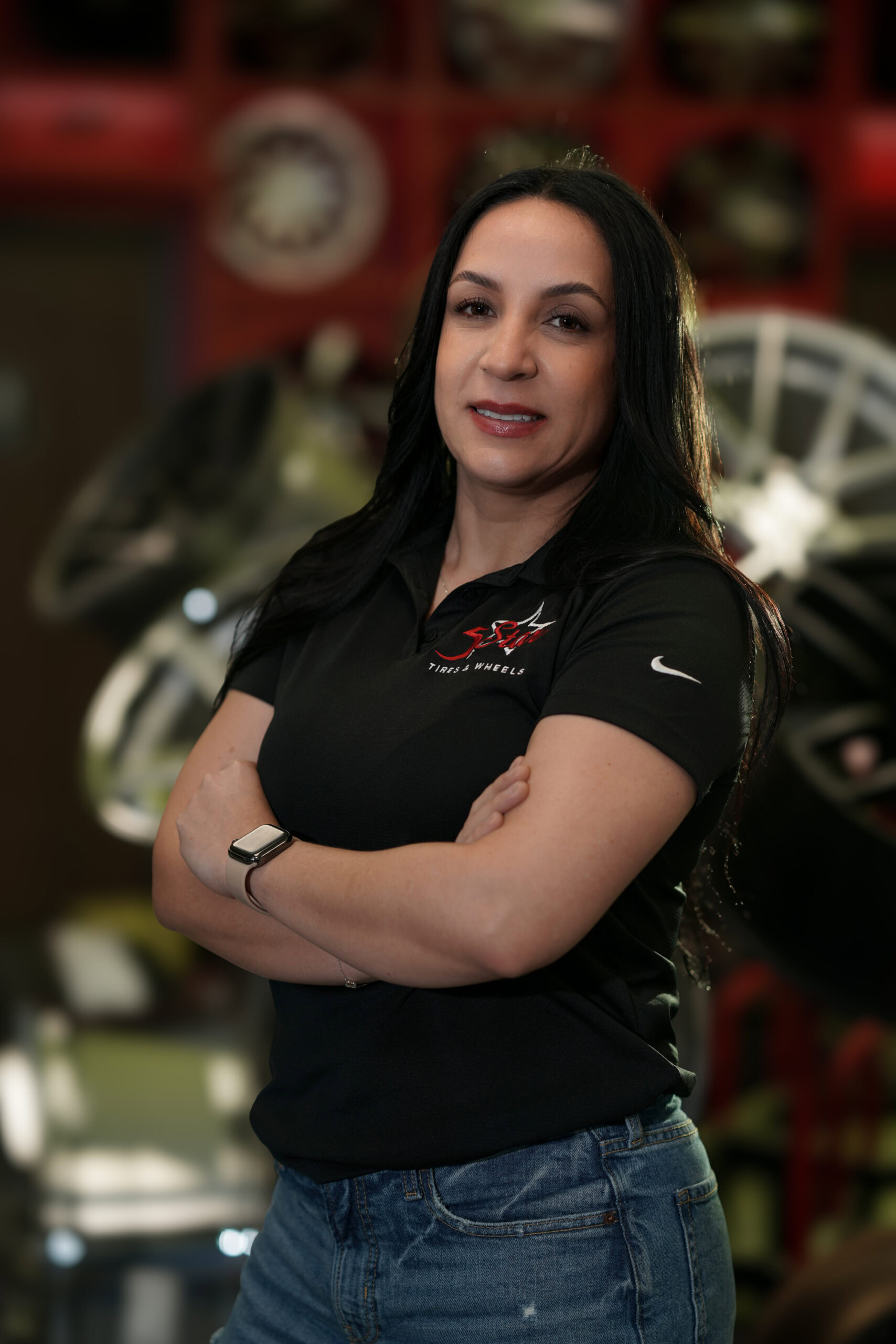 Confident woman in black uniform at 5 Star Tires and Wheels, automotive expert.