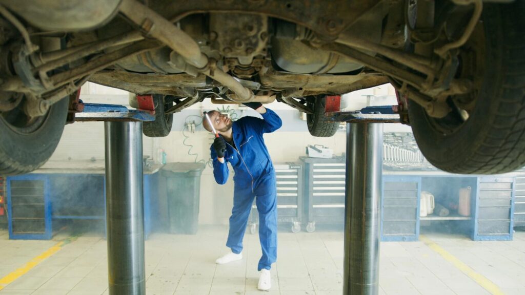 Clutch repair inspection under a car in a repair shop.
