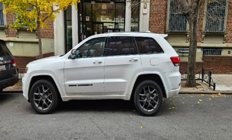 Luxury SUV parked on city street in front of building.