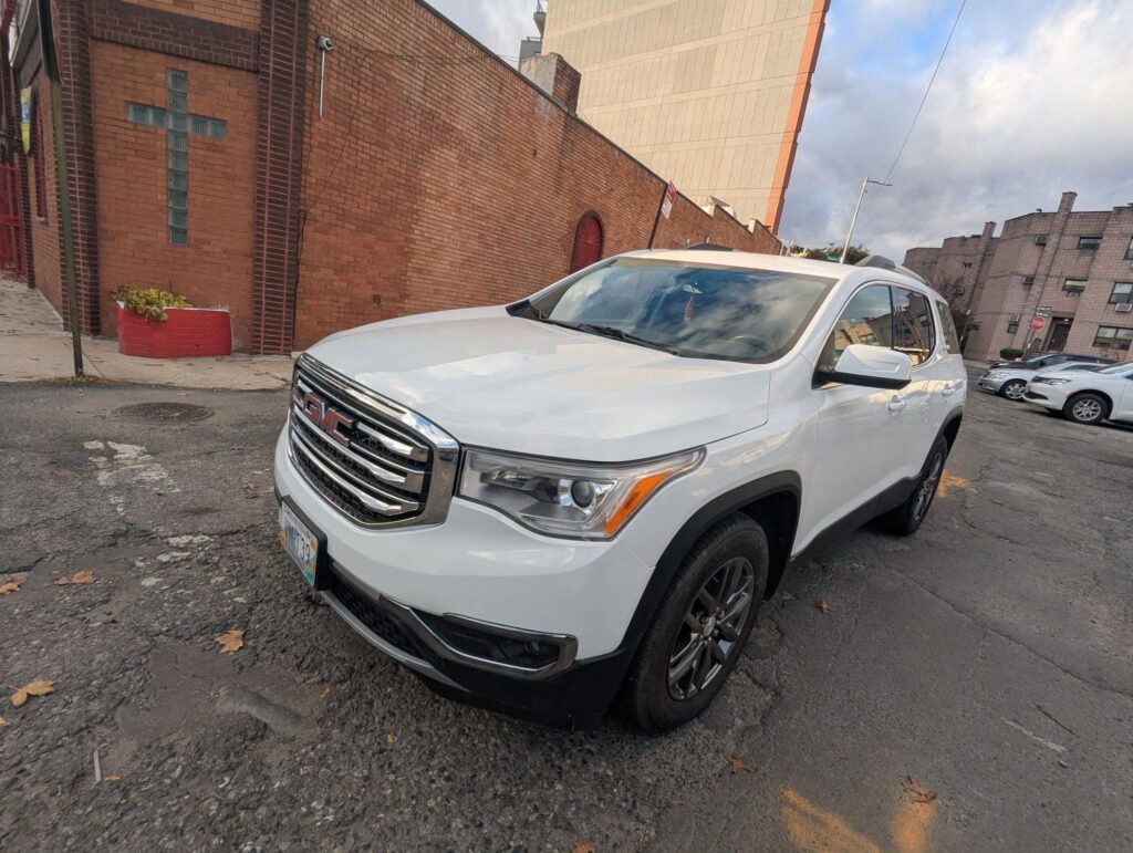 GMC Terrain SUV parked on street outside auto repair shop.