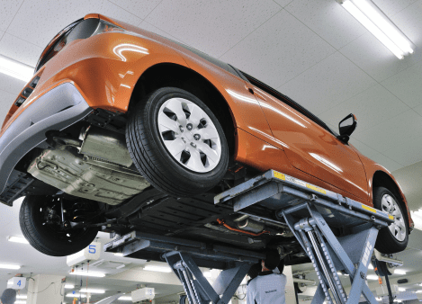Modern orange car lifted on hydraulic lift at A1 Auto Care.