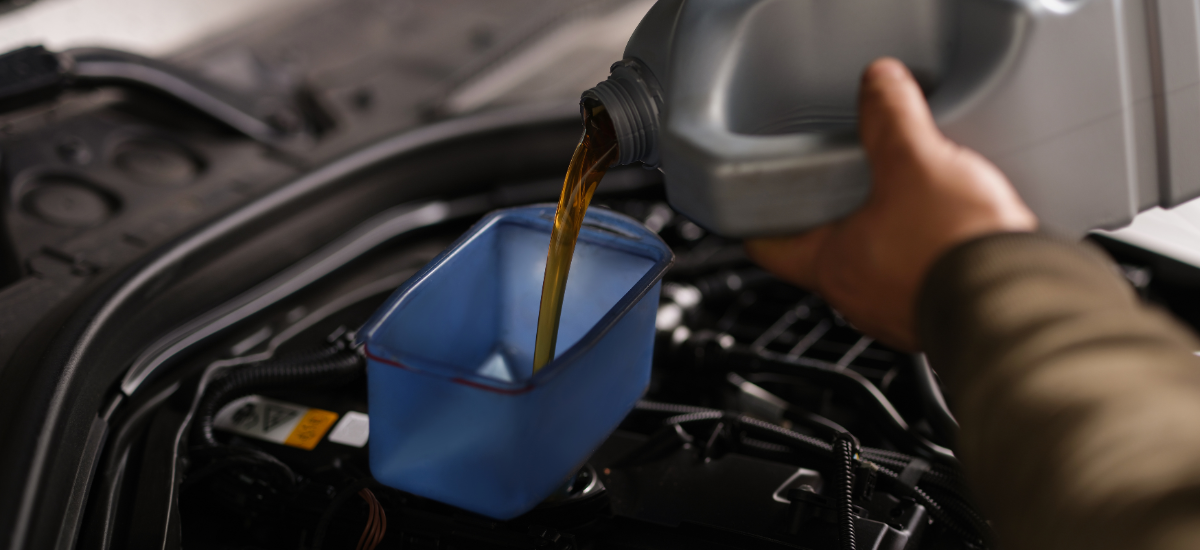 Pouring engine oil into a car engine during maintenance.