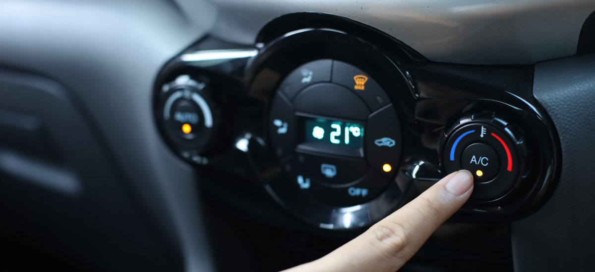 Person adjusting car air conditioning control for optimal climate comfort.