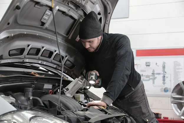 Auto mechanic inspecting engine for better fuel economy.