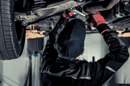 Technician inspecting vehicle transmission system under the car.