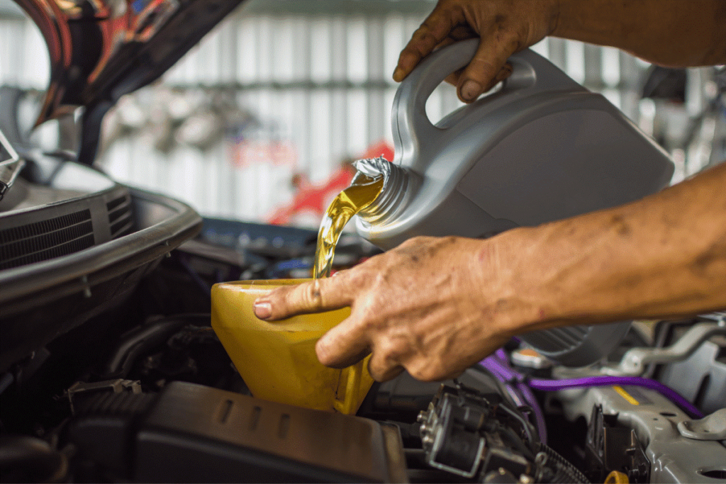 Technician pouring new transmission fluid into a vehicle engine at AA Transmission.