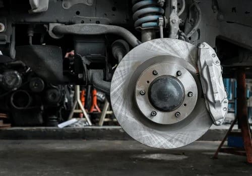 Close-up of a car's disc brake and suspension system at AA Transmission repair shop.