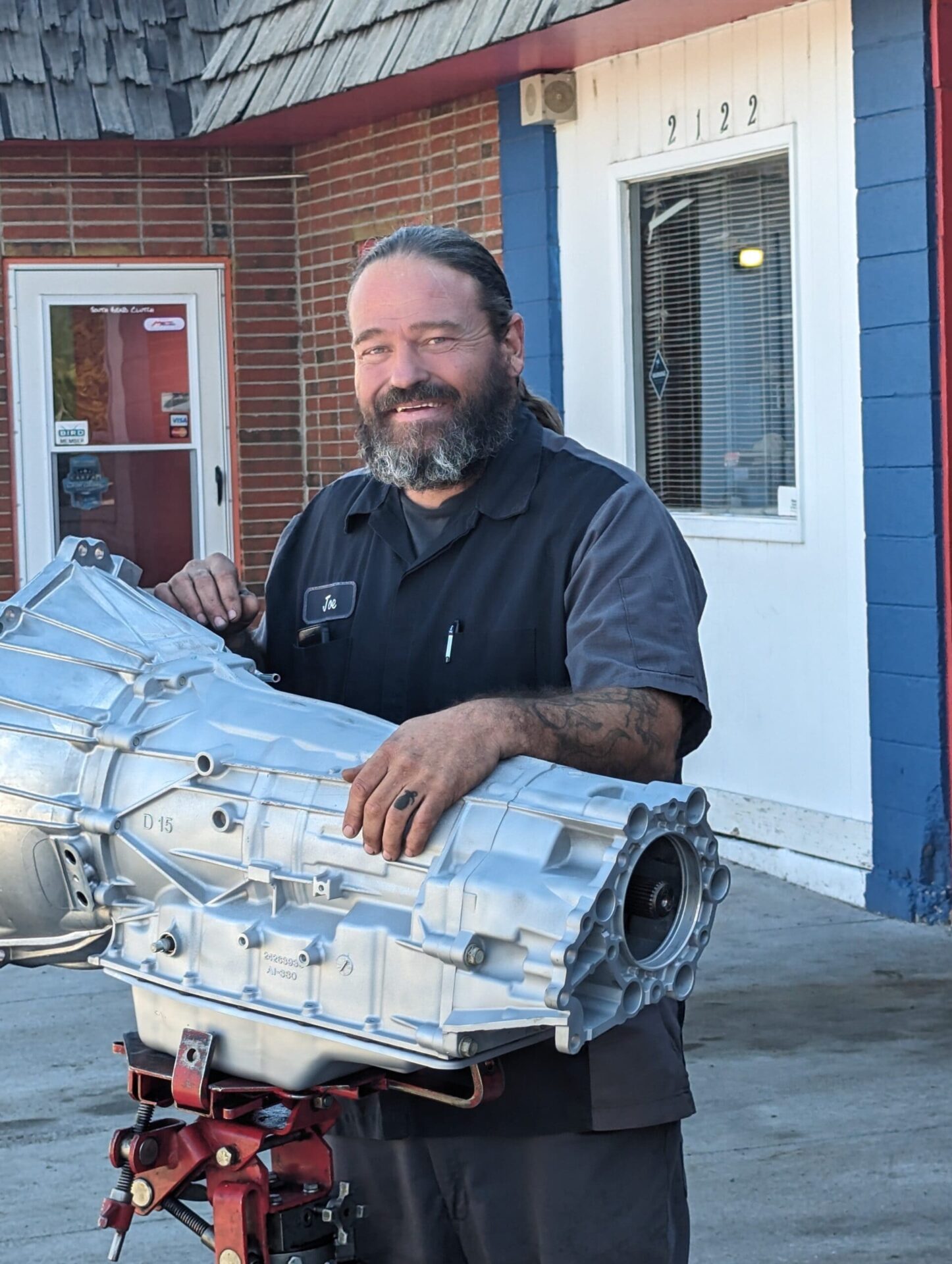 Transmission repair expert holding transmission unit at AA Transmission.