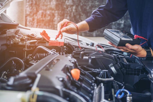 Technician testing car transmission with diagnostic tools at AA Transmission shop.