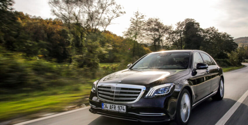 Mercedes-Benz luxury car on the move in a natural landscape.