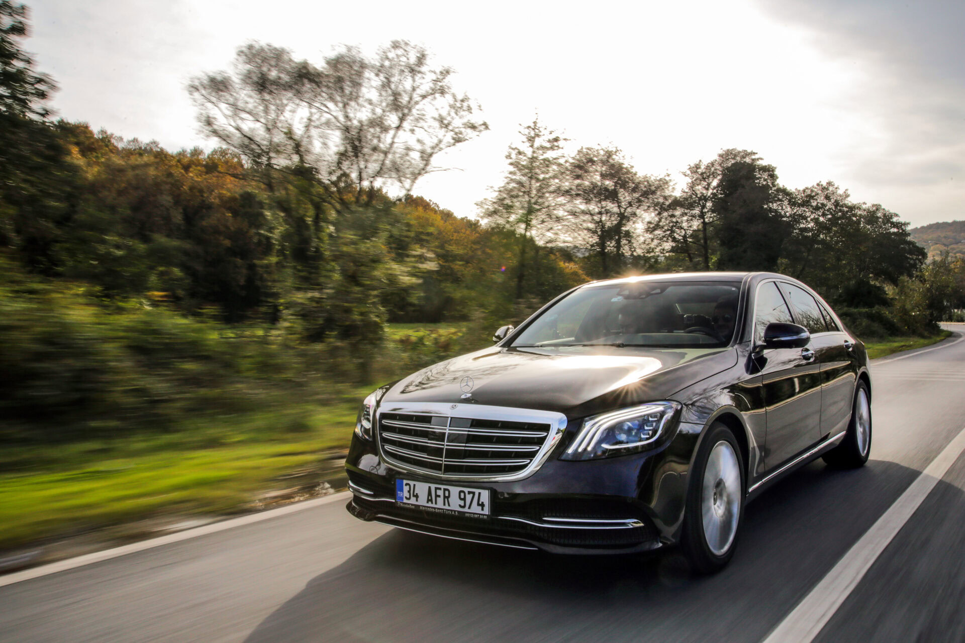 Mercedes-Benz luxury car on the move in a natural landscape.