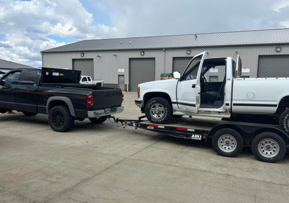 Auto repair tow truck transporting a white pickup truck at Above All Auto Repair.