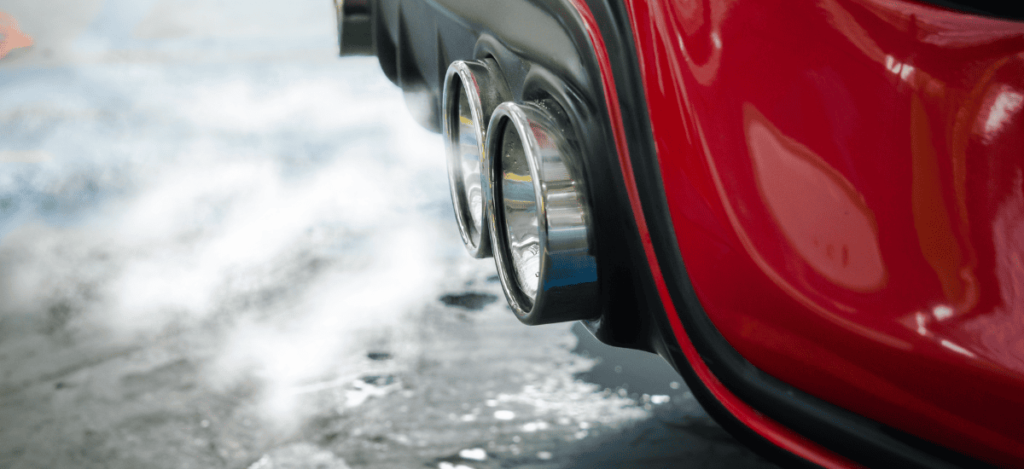 Close-up of a sports car exhaust pipes on a red vehicle, showcasing high-performance automotive part.