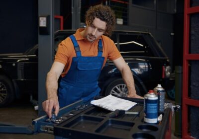 Engine repair technician inspecting car engine at auto repair shop.