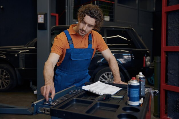 Engine repair technician inspecting car engine at auto repair shop.