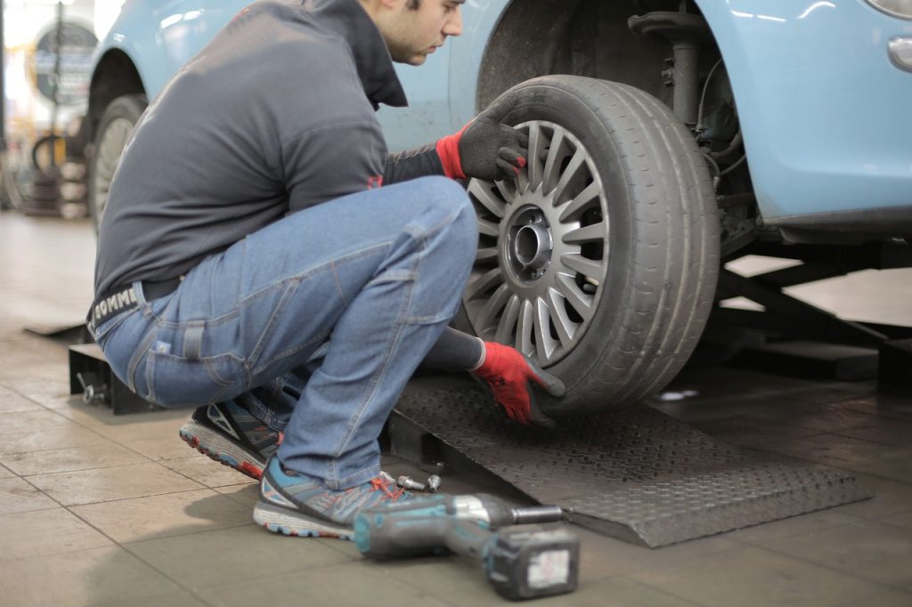 Auto mechanic inspecting car tire for damage and wear.