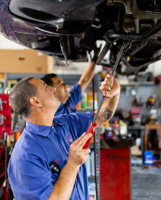 Auto repair technician inspecting vehicle undercarriage in Aliso Viejo.