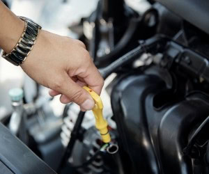Engine oil dipstick being checked in a vehicle.