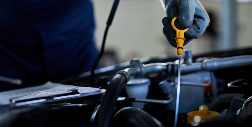 Technician checking engine oil level during vehicle maintenance in Aliso Viejo.