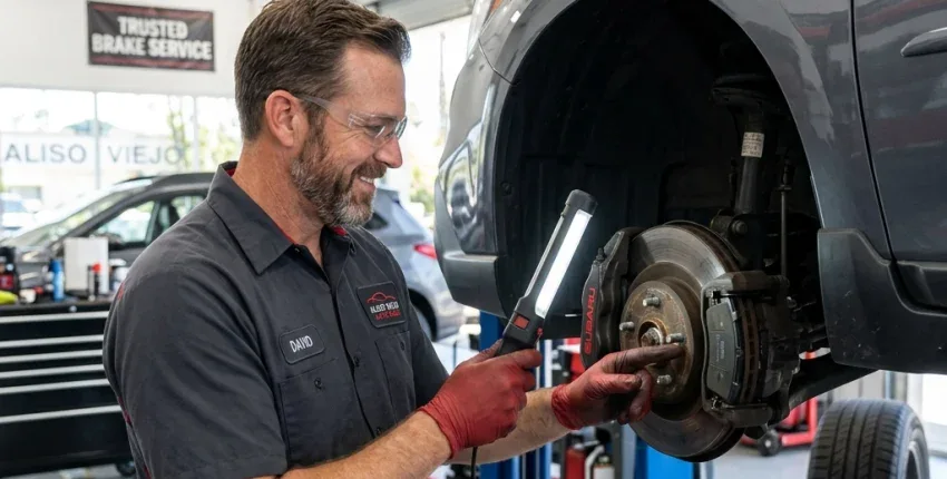 Auto mechanic inspecting brake system on vehicle in Aliso Viejo shop.