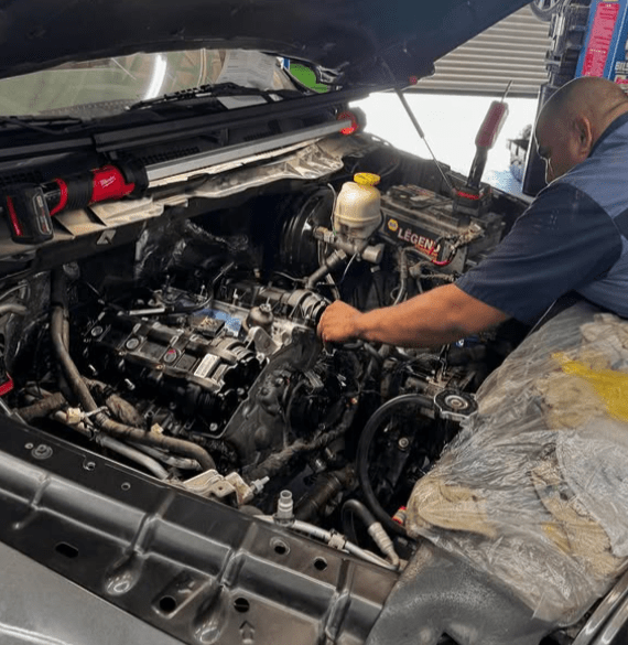 Skilled mechanic working on car engine at Al’s Automotive repair shop.