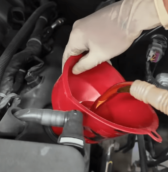 Technician pouring oil into engine during vehicle maintenance at Al’s Automotive.
