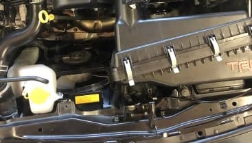 Engine bay of a modern vehicle showing engine components and air intake system.