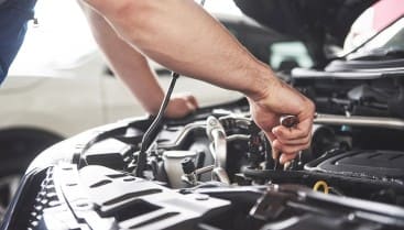 Auto repair technician working on car engine at Al’s Automotive.