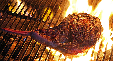 Closeup of tomahawk rib eye on a flaming grill