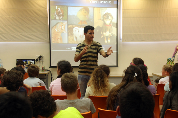 man giving lecture to kids with a slideshow about animals behind him