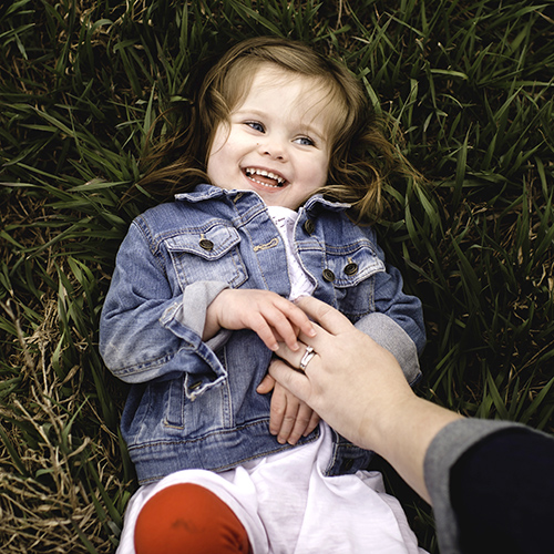 אמא מדגדגת ילדה על הדשא