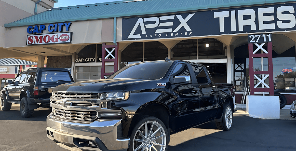 Apex Auto Center, a trusted tire and auto repair shop, featuring a black pickup truck parked outside.