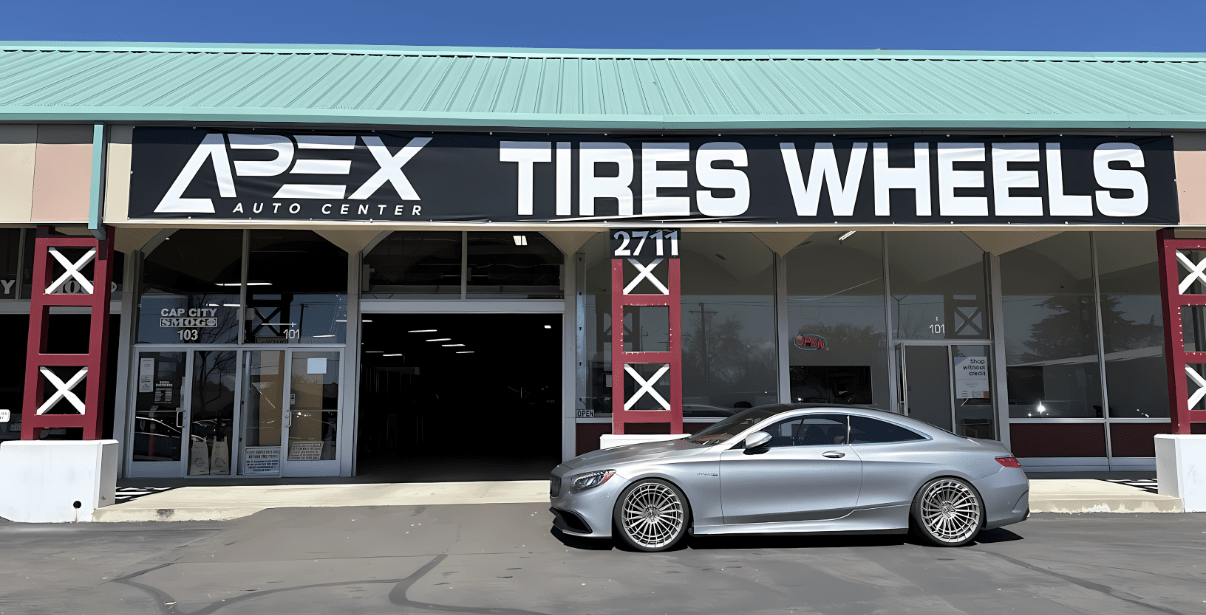 Apex Auto Center tire and wheel shop with a silver car parked outside.