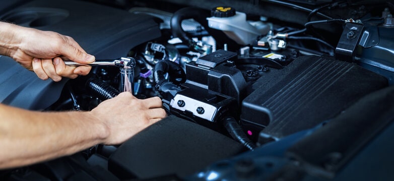 Technician performing engine diagnostics and repairs on a modern vehicle engine.