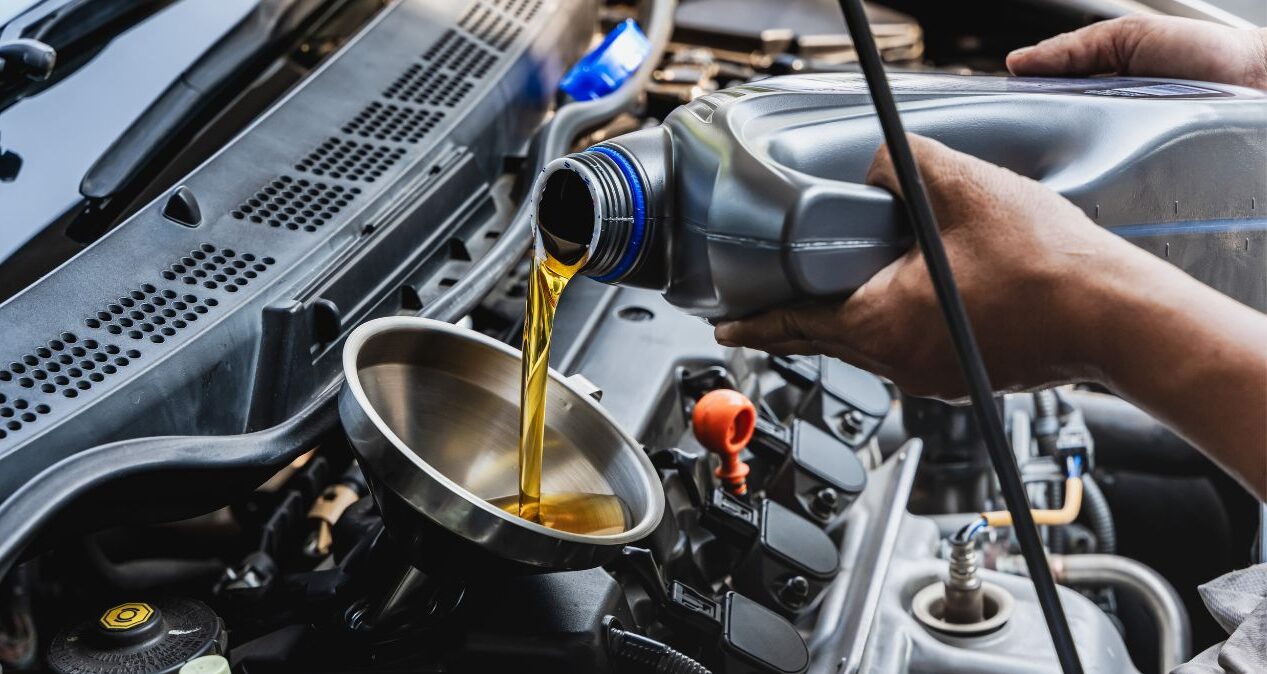 Mechanic pouring engine oil into a car during maintenance.