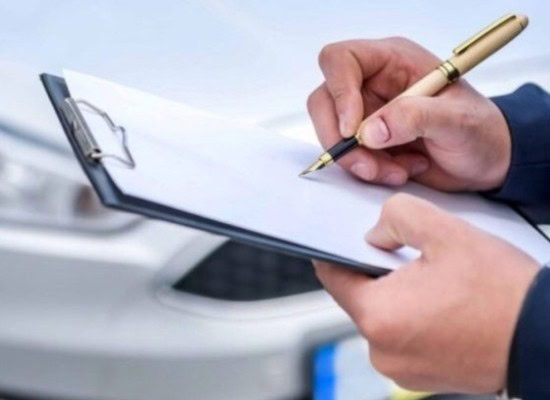 Technician writing vehicle inspection details on clipboard at Army Mechanics Inc.