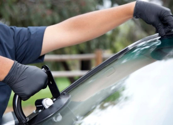 Auto glass repair technician replacing windshield glass.
