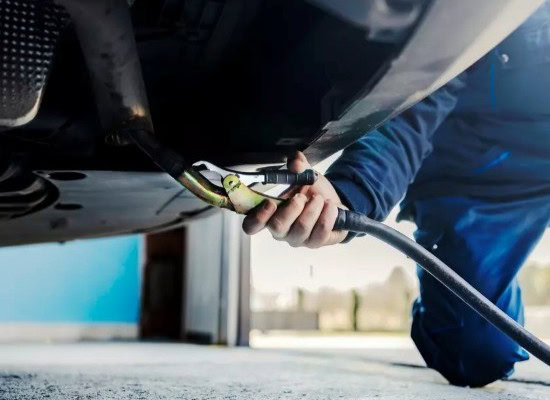 Automotive inspection technician checking under vehicle for safety and performance.
