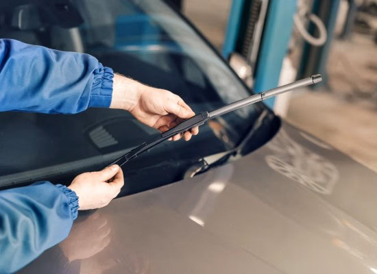 Auto repair technician inspecting a car windshield with a tool.