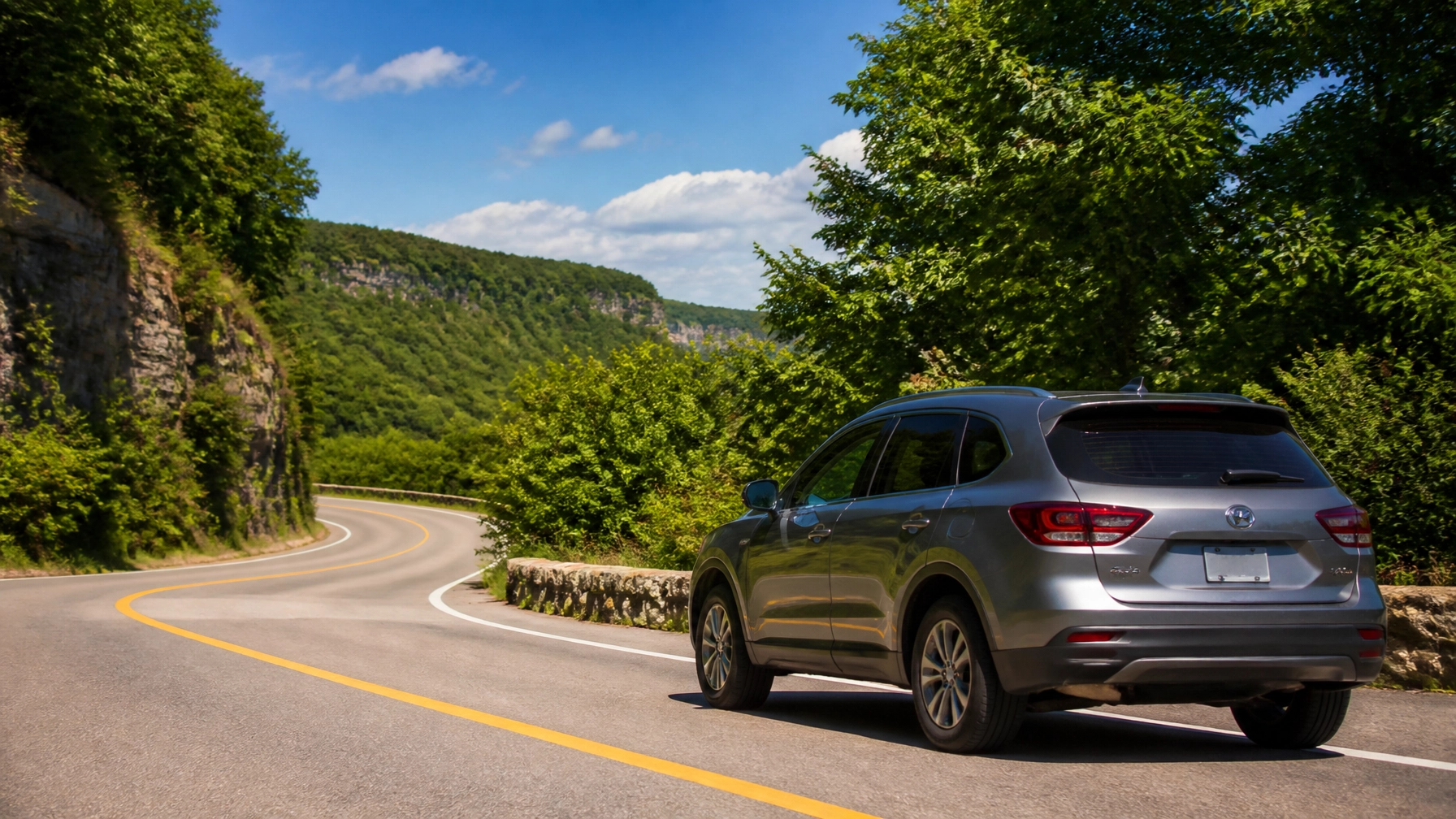 SUV parked on a winding mountain road surrounded by lush greenery.