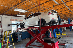 Skilled technicians performing engine repairs on a white car in a professional auto shop.