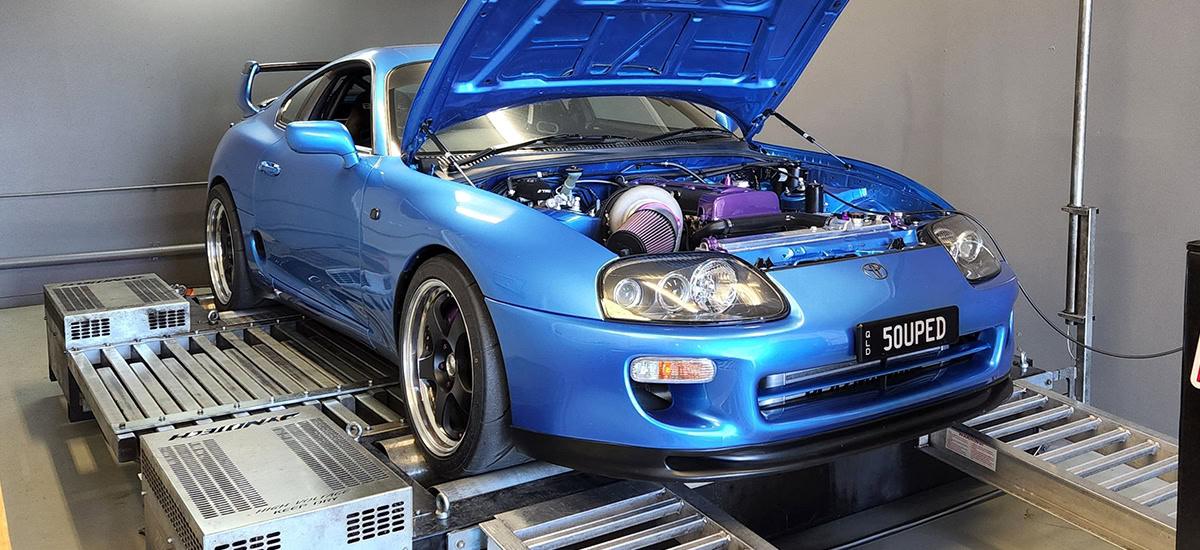 Blue sports car undergoing performance testing on a dynamometer.