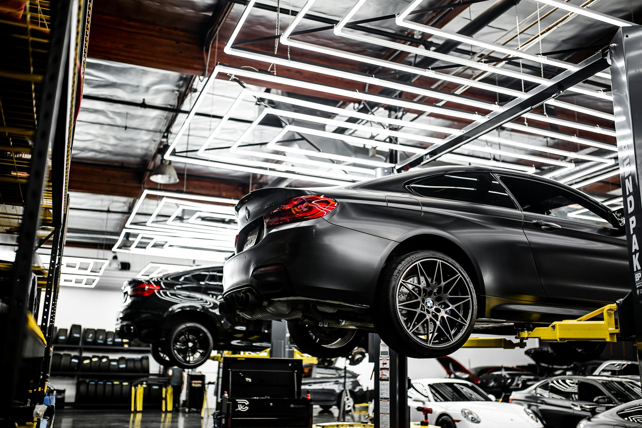 Modern automotive service shop with luxury cars on lifts, specializing in performance upgrades and r.