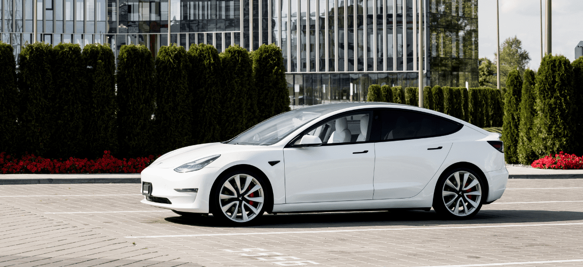 Tesla Model 3 electric car parked outdoors with modern office buildings in the background.