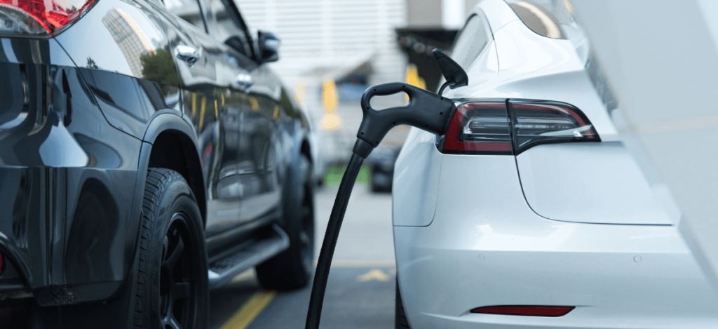 Electric vehicle charging station with a white car plugged in for charging.