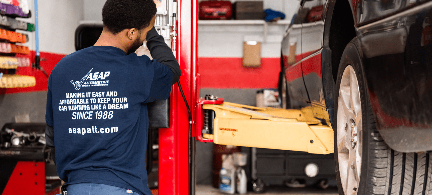 Technician inspecting a car lifted on a hydraulic lift at ASAP Automotive & Transmission.